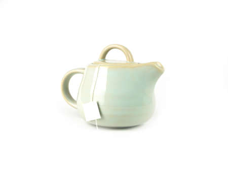 Ivory color ceramic teapot with a tea bag inside and white label isolated on a white background, Asian food concept with copy space.の写真素材