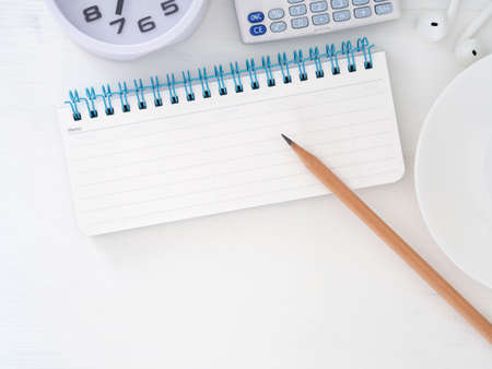 Blank notebook with pencil and clock, calculator on white office desk. Top view with space for text. Flat lay. Business education concept.の写真素材