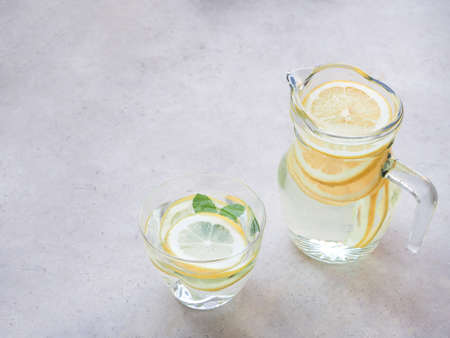 Lemons slice and water in glass, jar with mint leaves on grey background, drink for detox, and refresh the body.の写真素材