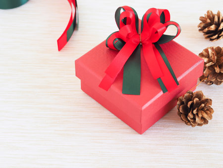 Red gift box with a bow and golden pine cone, ribbon on white fabric with copy space. Concepts for holiday. Christmas background.の写真素材