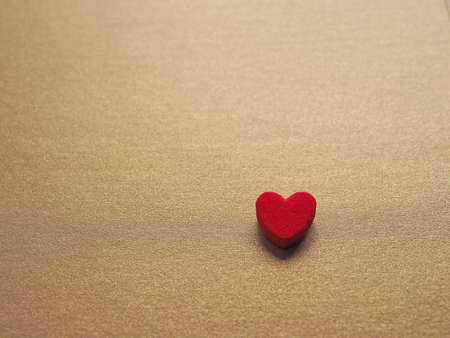 Red heart on glittering gold paper background. Concept for love and encouragement.の写真素材