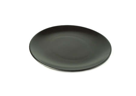 Empty black plate isolated on a white backgruond. Use for home or restaurant, food design. Kitchen accessory.の写真素材