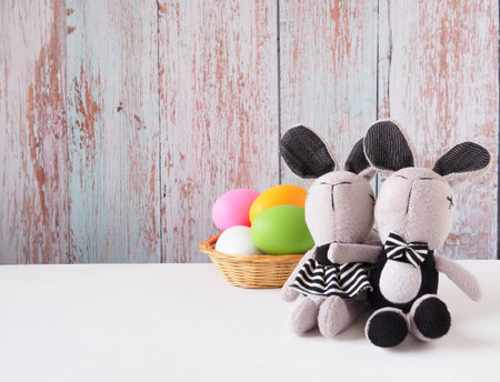 Easter bunny rabbit and multi colored eggs in basket on a white wooden background with copy space. Festive concepts.の写真素材