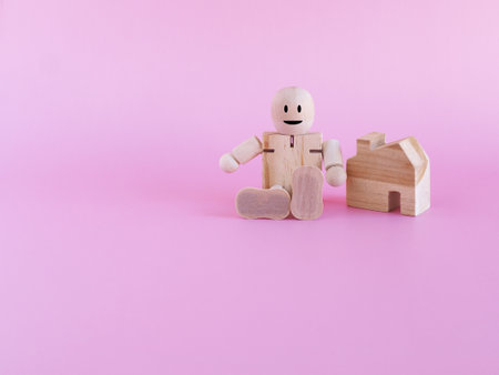 Wooden doll and house on pink background with space for you text. The concept investment, financial, New normal.の写真素材