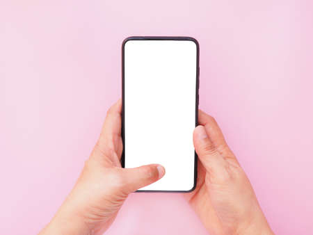 The hand-holding smartphone shows a white screen display on pink background. Top view, flat lay with copy space.の写真素材