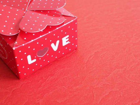 Red gift box with the word LOVE on paper background. Close up, with copy space. Concepts Valentine's...