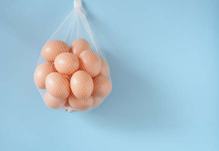 Easter eggs in a mesh bag on a blue background with copy space. Festive concepts. Top view, flat lay.の写真素材