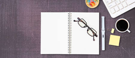 Flat lay office wooden desktop with blank notebook and eyeglasses with pen, Stationery equipment and coffee. Top view with space for text. Business and education concept.の写真素材