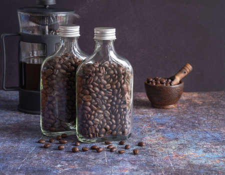 Roasted coffee beans in glass bottle with bowl wooden and coffee pot on grunge background. space for your text.の写真素材
