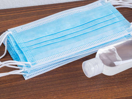 Medical face mask and hand sanitizer alcohol gel on brown  background. Concept of coronavirus outbreak and pollution. New normal.の写真素材