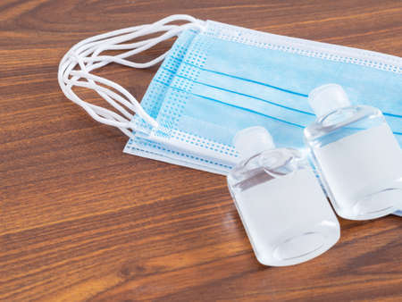 Medical face mask and hand sanitizer alcohol gel on brown  background. Concept of virus outbreak and pollution. New normal.の写真素材