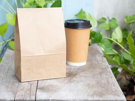 Roasted coffee beans in craft paper bag with cup on wooden table. Mouckup, template with copy space for your text or logo.の写真素材