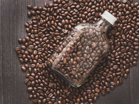 Top view, flat lay roasted coffee beans in glass bottle over pile of beans background, space for your text.の写真素材