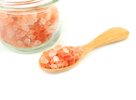 Himalayan pink salt in wooden spoon with glass bottle isolated on a white background. Space for text.の写真素材