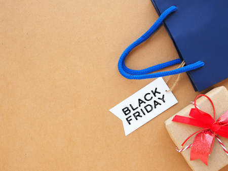 Top view, white tag with the word "Black Friday" and blue shopping bag, gift box on craft paper background. Flat lay, copy space.の写真素材