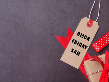 Brown cardboard label or tag tied with string has the word Black Friday and gift box, red ribbon on...