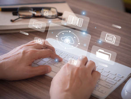 Cloud Computing Concept. Hand typing keyboard show virtual screen with icon cloud computing, file, and security network in the workplace.の写真素材