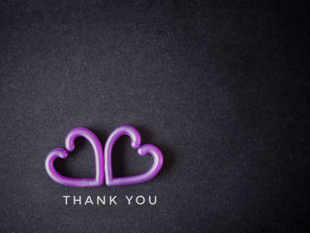 The words "thank you" message with purple two hearts on the black paper background. Top view, flat lay with copy space. Greeting card.の写真素材