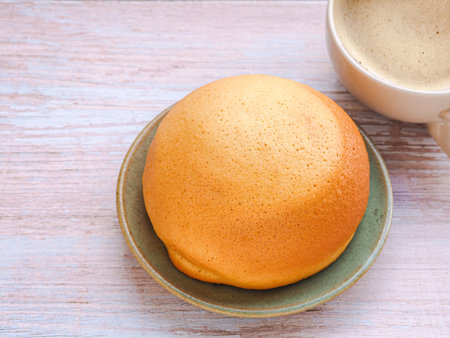 Homemade mexican vanilla bun (coffee bun) on turquoise clay round plate and coffee cup over rustic table. space for your text.の写真素材