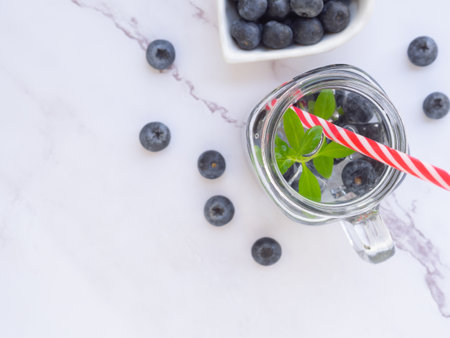 Infused water with fresh organic blueberries and drinking straw on marble background. Space for your text. Top view, flat lay.の写真素材
