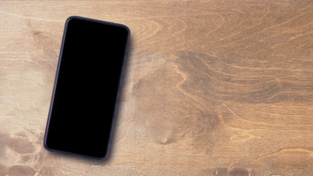 Concept for website, social media, and design. High angle view blank screen smartphone on wooden background. Top view, flat lay with copy space for banner.の写真素材