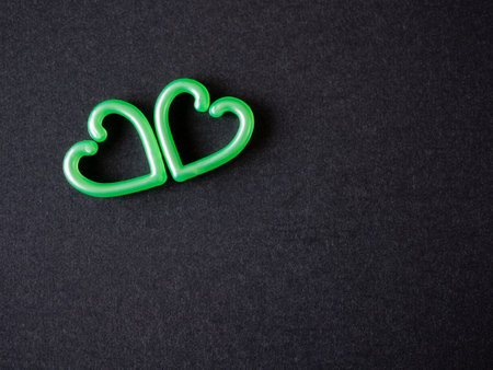 Two green heart on the black paper background. top view, flat lay with copy space. Greeting card.の写真素材