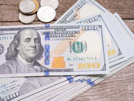 American one hundred dollar banknote and coin stack on wooden table. Close-up money background.  Business, finance, investment and savings concept.の写真素材