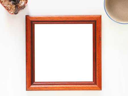 Empty picture frame wooden square shape with coffe cup, and cactus on a white background. Anniversary, valentine, wedding, and mother day concept. Top view, photo frame for template.の写真素材