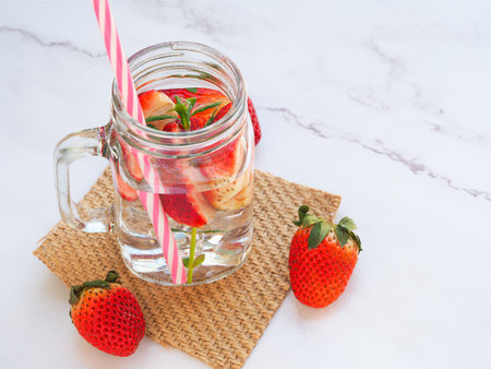 Infused water with fresh organic strawberry and drinking straw on marble background. Space for your text.の写真素材