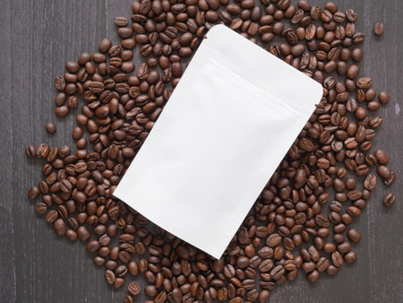 Flat lay, top down, Roasted coffee beans in white paper bag with zipper over a pile of beans.の写真素材