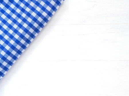 Top view, close-up of blue and white checkered fabric or napkin on white table background. Concept kitchen utensils and tableware. Top view, flat lay with copy space.の写真素材
