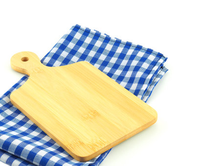 Empty cutting board on blue and white checkered fabric or napkin isolated on white background. Concept kitchen utensils and tableware.の写真素材