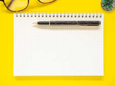 Top view, Flat office yellow workplace with notebook and pen. Copy space for your text. Business and education concept.の写真素材