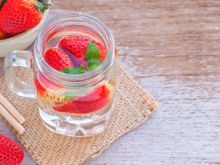 Infused water with fresh organic strawberry and drinking straw on rustic wooden background. Space for your text.の写真素材