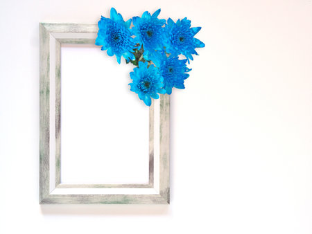 Grey rectangle border photo frame and blue flowers (chrysanthemum) on white background. Top view, flat lay with copy space.の写真素材