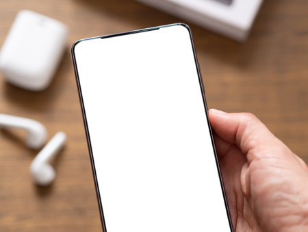 Hand holding blank screen of the smartphone over earphone blur background with copy space. Mobile phone template.の写真素材