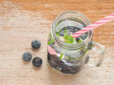 Top view, Infused water with fresh organic blueberries and drinking straw on wooden background. Space for your text. Top view, flat lay.の写真素材