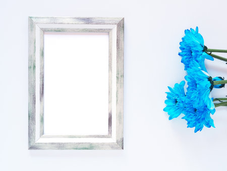 Grey rectangle border photo frame and blue flowers (chrysanthemum) on white background. Top view, flat lay with copy space.の写真素材