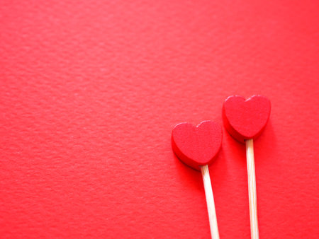 Two wooden hearts on red paper background. Valentine's day background. Top view with copy space. Positive background.の写真素材
