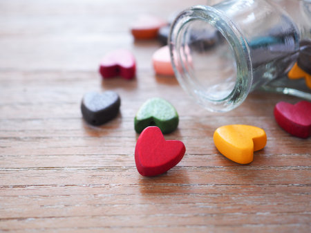 Red wooden heart and glass bottle with hearts in it, selective focus. Positive and love emotion background.の写真素材