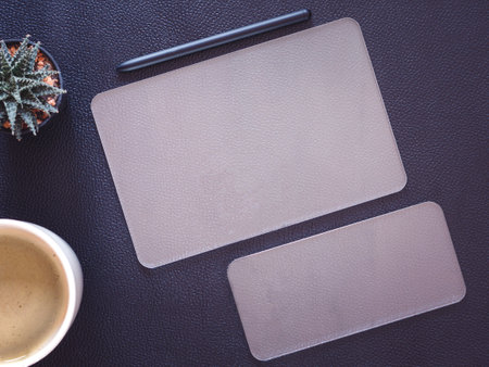 Top view, mock-up transparent digital tablet pc computer with transparent smartphone, wireless pen and cactus, coffee cup. Business concept and technology.の写真素材