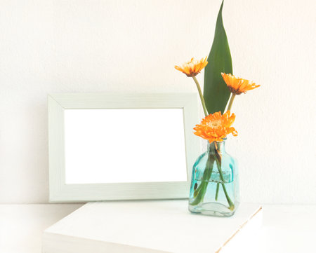 Light green rectangle border photo frame and orange chrysanthemum blooming on table.の写真素材