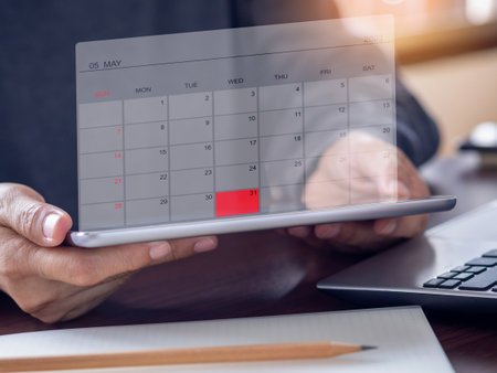 Businessmen use tablet pc show calendar application on virtual screen showing May 2023 and mark red color on the date 31st. Calendar app with planning and reminder concept. Business background.の写真素材