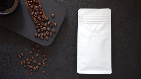 Mock-up, Roasted coffee beans in white plastic zipper bag and cup on black table leather. Packaging template for product. Top view, flat lay.の写真素材