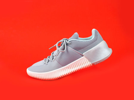 Modern gray-light green sneakers for men or women (unisex) isolated on a red background. Fashion style pair of casual sports shoes, Mock-up for sneaker design, a product of sport.の写真素材