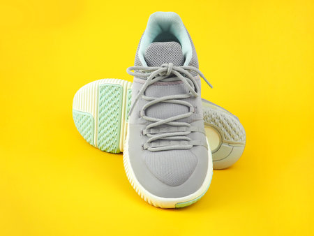 Modern gray-light green sneakers for men or women (unisex) isolated on a yellow background. Fashion style pair of casual sports shoes, Mock-up for sneaker design, a product of sport.の写真素材