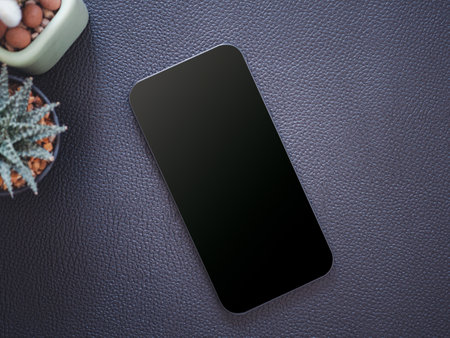 Top view, blank black screen of smartphone and cactus on the black leather background. Template, mock-up empty screen of mobile phone for text and logo of product.の写真素材