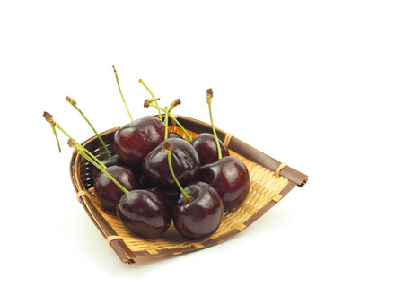 Fresh cherries on wicker besket isolated on white background.の写真素材