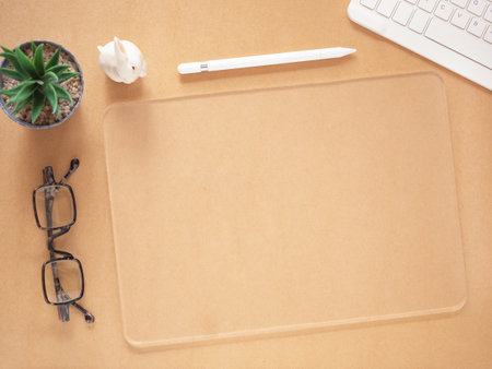 Top view, flat lay transparent tablet pc and keyboard, glasses, cactus, pen on brown workplace. Copy space for advertising of products, text, and design. Business and education concept.の写真素材