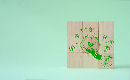 Green energy symbols on a wooden cube on a green background. Net zero greenhouse gas emissions target to reduce global warming in a sustainable future in 2050.の写真素材